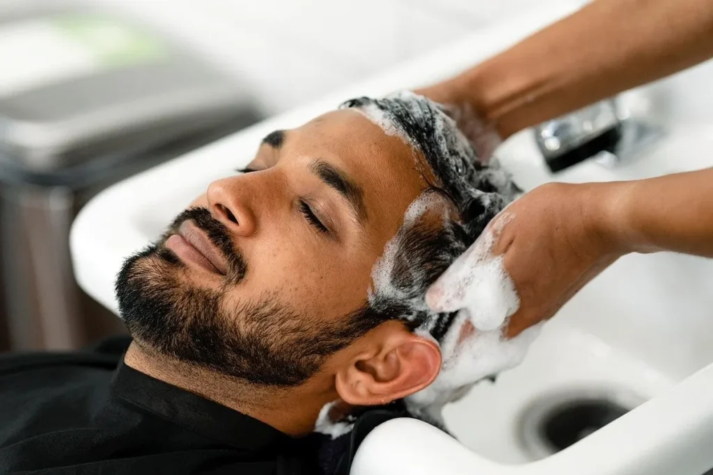 Barber washing a man’s hair during a professional scalp care treatment