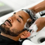 Barber washing a man’s hair during a professional scalp care treatment